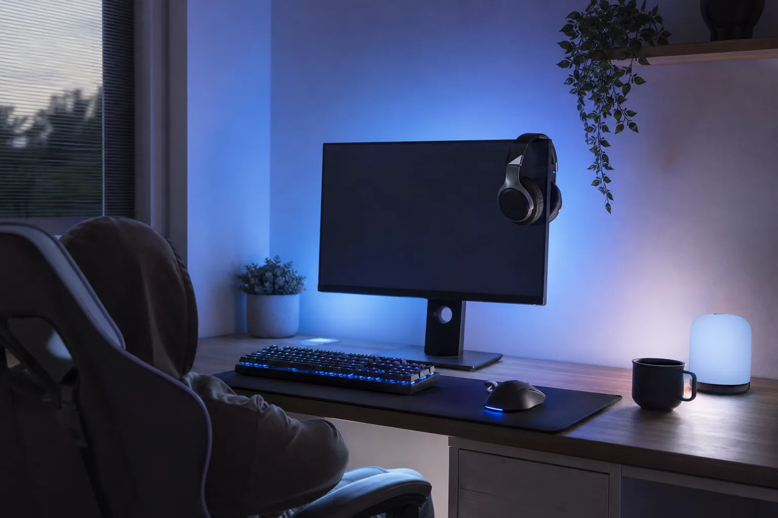 Gamingtangentbord och headset framför en avstängd skärm i en spelhörna på kvällen