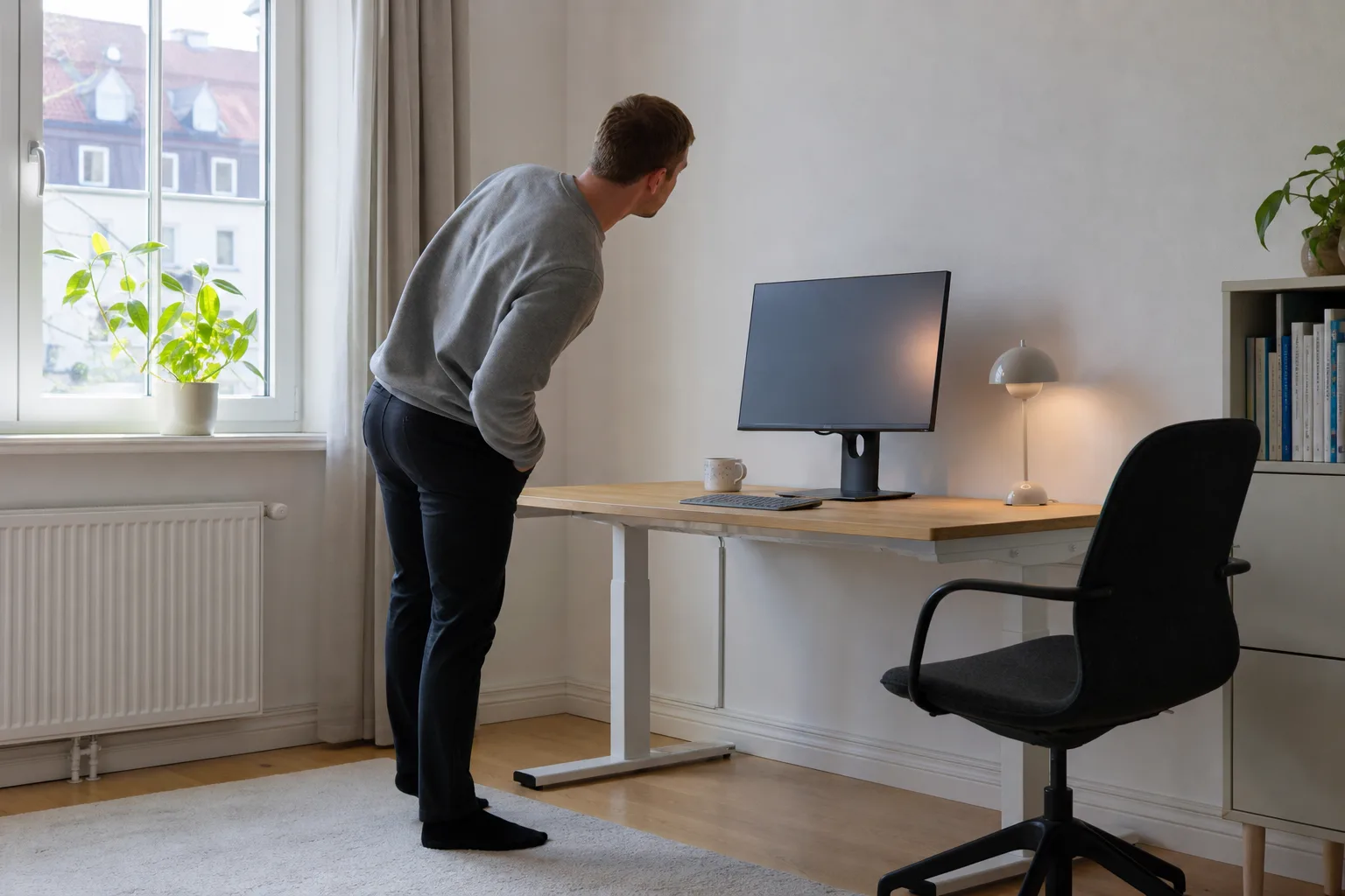 Person sedd från sidan lutar sig för att titta på en avstängd skärm snett från sidan
